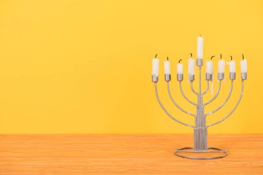 close up view of menorah with candles for hannukah holiday celebration on wooden tabletop isolated on yellow, hannukah concept clipart