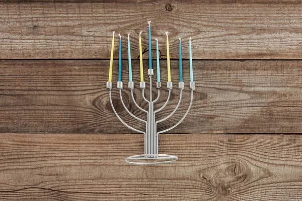 在木制桌面上的传统犹太灯台与蓝色和黄色蜡烛的顶部视图 光明节假日概念 — 图库照片