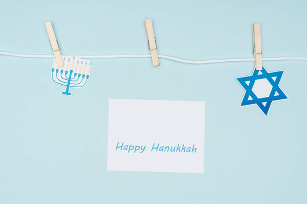 вид сверху на счастливую карту Hannukah и праздничные бумажные знаки привязанные на веревке изолированы на синий, Hannukah концепции
