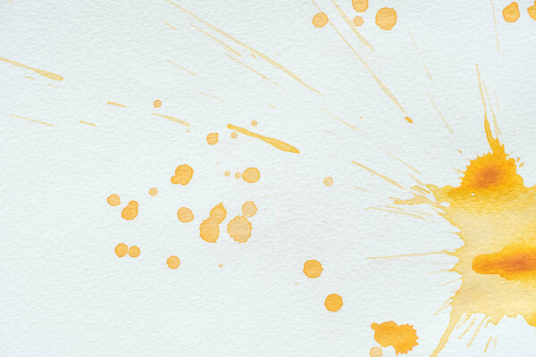 abstract orange watercolor splatters and blots on white paper