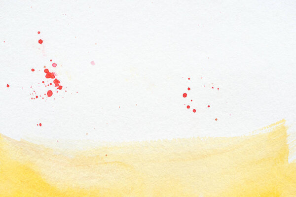 yellow watercolor stroke with red splatters on white paper background