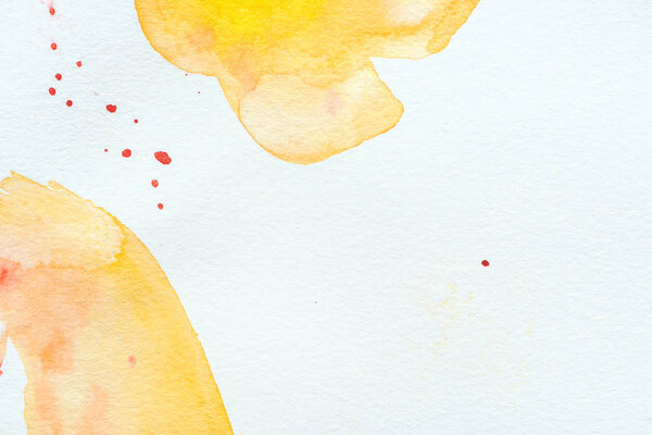 abstract yellow watercolor strokes with red splatters on white paper background