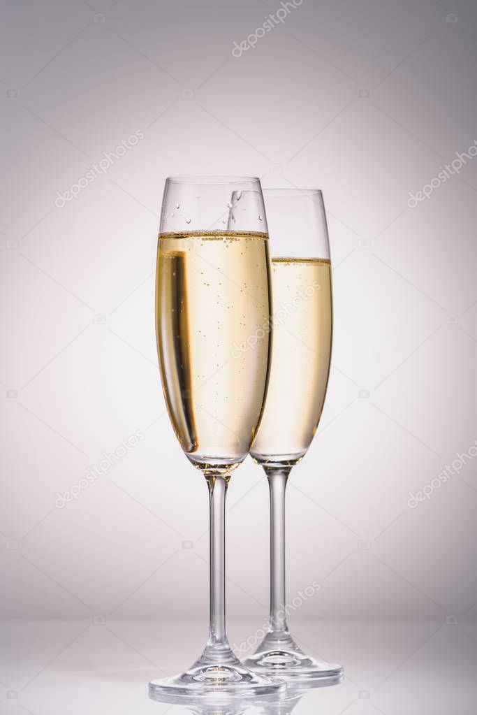 close up view of glasses of champagne on grey backdrop