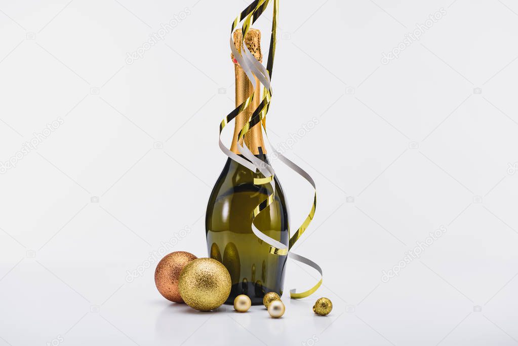 close up view of bottle of champagne with confetti and christmas toys on white backdrop