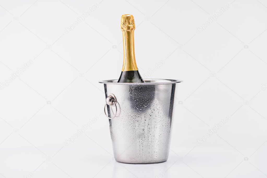 close up view of bottle of champagne in bucket on grey backdrop