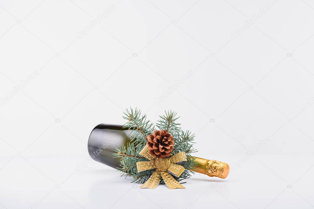 close up view of bottle of champagne with christmas decoration on white background
