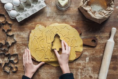 kadın kesme çiğ hamur Noel kurabiyeleri ahşap yüzeyde hazırlanırken çerez kesici ile kısmi görünümü
