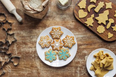 düz lay Noel kurabiyeleri plaka, malzemeler ve ahşap masa üzerinde düzenlenmiş çerez kesici ile