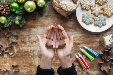 kısmi köknar ağacı tutan kadın görünümünü şeklinde çerez kesici ile Noel çelenk ve malzemeler ahşap masa üzerinde elinde