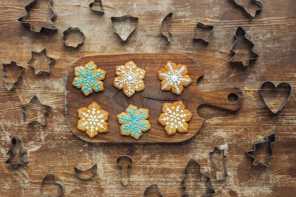 平躺在切割板上的圣诞饼干和木制表面周围的饼干切割机 — 免费的图库照片