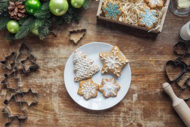düz lay ile Noel kurabiyeleri Noel dekoratif çelenk, oklava ve çerez kesici ile ahşap yüzeyde plaka üzerinde