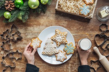 kısmi görünümünü bardak süt ve kurabiye dekoratif Noel çelenk ve karton kutu ile ahşap masa üzerinde tutan kadın