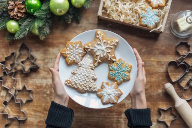 kısmi görünümü ile ev yapımı kurabiye plaka dekoratif Noel çelenk ve karton kutu ile ahşap masa üzerinde tutan kadın