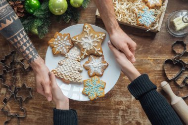 kısmi görünümü ile ev yapımı kurabiye plaka dekoratif Noel çelenk ile ahşap masa üzerinde tutan kadın ve erkek