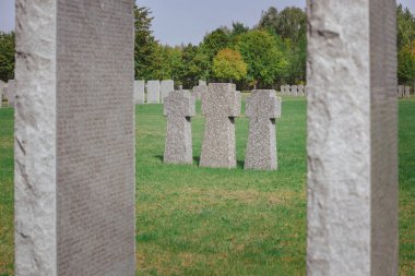 selective focus of identical memorial stone crosses placed in row at graveyard clipart