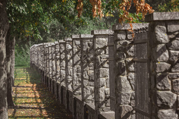 selective focus of stone fence under trees outdoors 