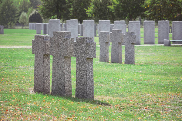 rows of identical old gravestones on grass at graveyard