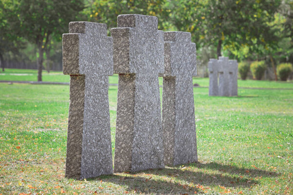 close up view of identical old gravestones placed in row on grass at cemetery