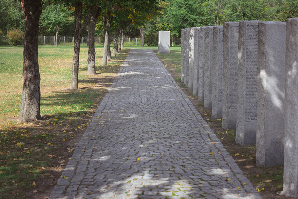 path from paving stone and memorial headstones placed in row at cemetery