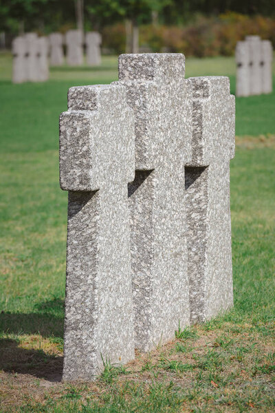 close up view of identical memorial stone crosses placed in row at cemetery