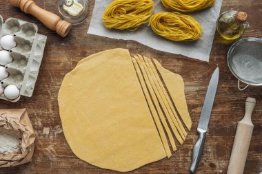 top view of cut raw dough for pasta on wooden table clipart