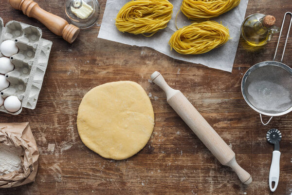 top view of uncooked pasta ingredients and utensils on wooden table