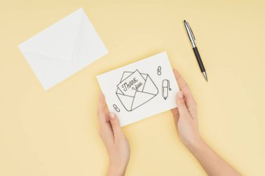 Kağıt üzerinde sarı arka plan izole teşekkürler yazı ile tutan kişi kırpılmış