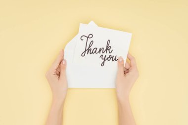 cropped person holding paper with thank you lettering isolated on yellow background clipart