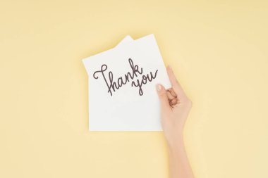 cropped person holding white postcard with thank you lettering isolated on yellow background clipart