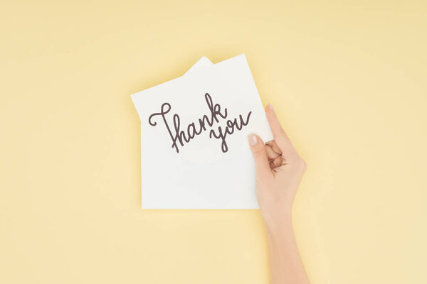 cropped person holding white postcard with thank you lettering isolated on yellow background