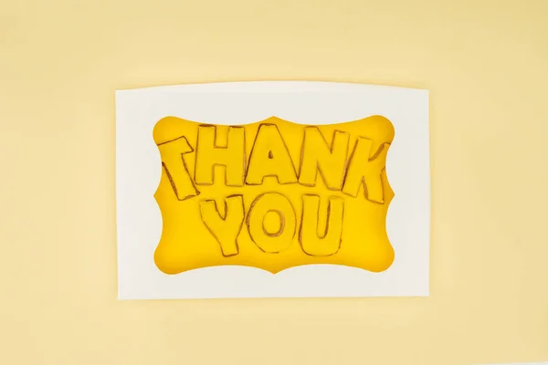 square-shaped cake in box with thank you lettering isolated on yellow background