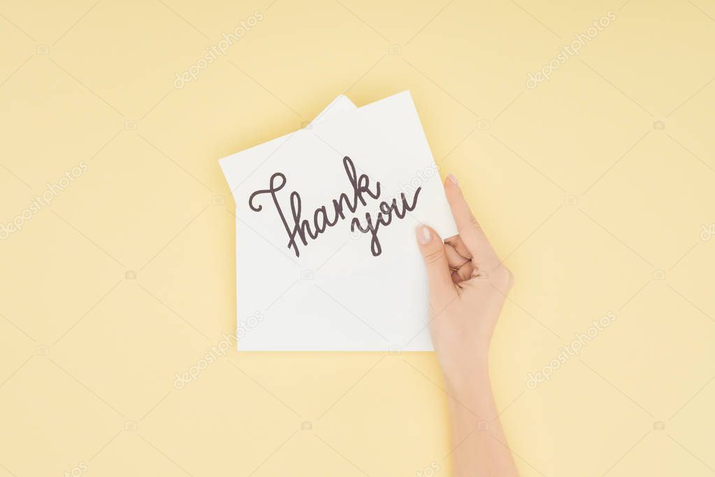 cropped person holding white postcard with thank you lettering isolated on yellow background