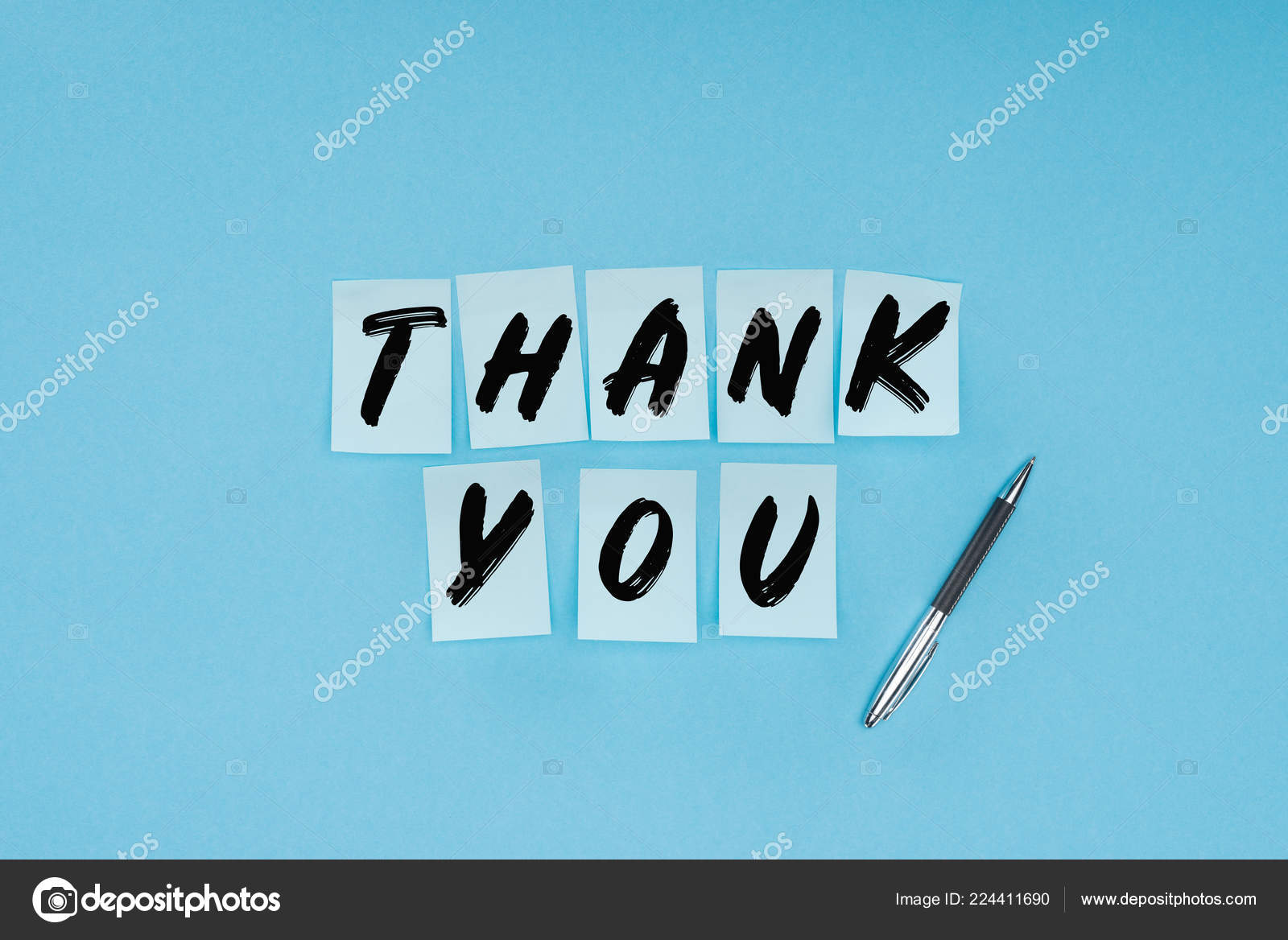 Thank you wording on sticky notes and pen isolated on blue background