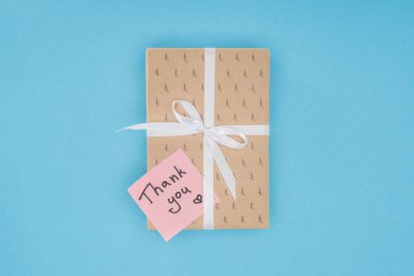 hediye kutusu ile mavi arka plan üzerinde izole teşekkürler yazı ile Yapışkan Not üstten görünüm 