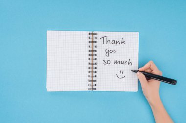 cropped person holding pen over notebook with thank you so much lettering isolated on blue background clipart