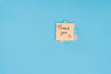 colorful sticky notes with thank you lettering isolated on blue background clipart