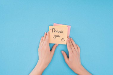 cropped person holding colorful sticky notes with thank you lettering isolated on blue background clipart