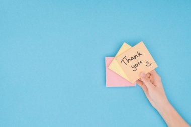 cropped person holding colorful sticky notes with thank you lettering isolated on blue background clipart