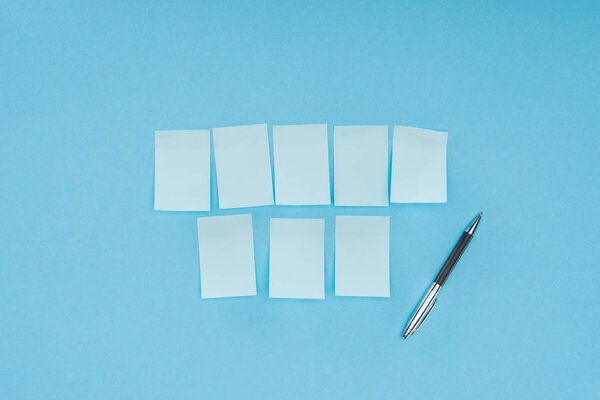 eight blank sticky notes with pen isolated on blue background
