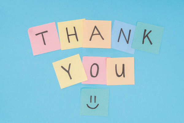 colorful sticky notes spelling thank you isolated on blue background