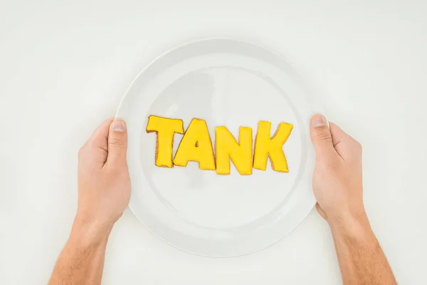 cropped person holding plate with tank word in yellow cookies isolated on white background