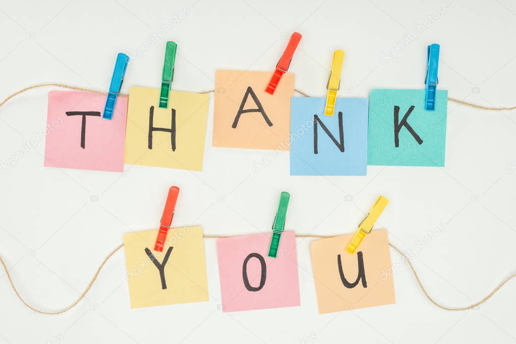 colorful sticky notes spelling thank you on lace with clothespins isolated on white background