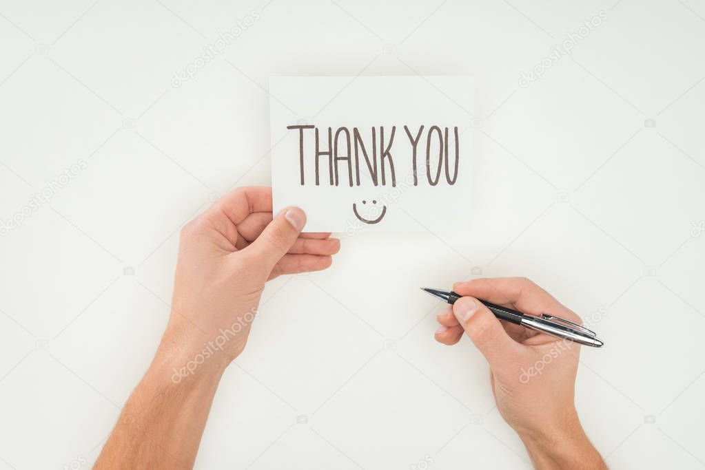 hands holding thank you lettering on white postcard and pen isolated on white background