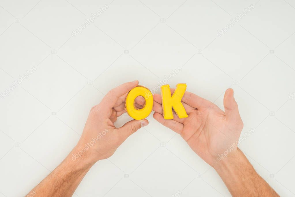 cropped person holding ok word in yellow cookies solated on white background