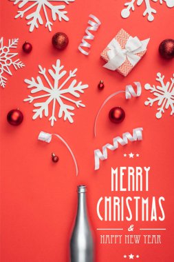 top view of present, champagne bottle, red christmas toys, white ribbons and decorative snowflakes arranged isolated on red with 