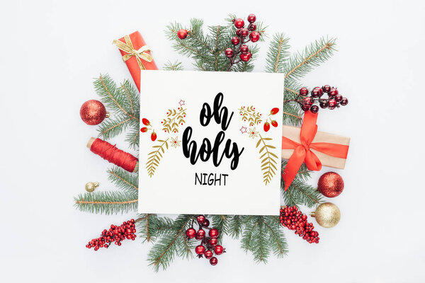 top view of pine tree branches, christmas decorations and gifts  with "oh holy night" lettering in middle isolated on white