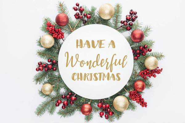 top view of pine tree wreath with Christmas decorations with "have a wonderful christmas" lettering in middle isolated on white