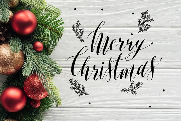 メリー クリスマス の文字と白い木製表面に赤のクリスマスのおもちゃと花輪のトップ ビュー — ストック写真
