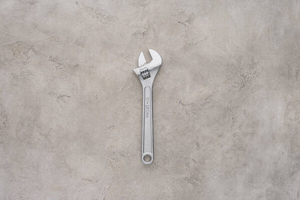 top view of adjustable pipe wrench lying on concrete surface