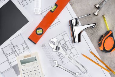 Sıhhi tesisat araçları ve hesap makinesi ile plan beton yüzeyinde binanın üstten görünüm